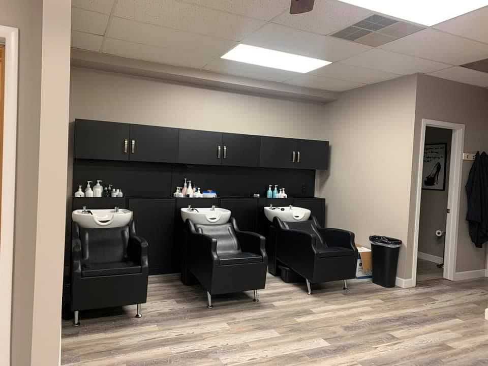 Modern hair salon interior with three wash stations and black chairs.