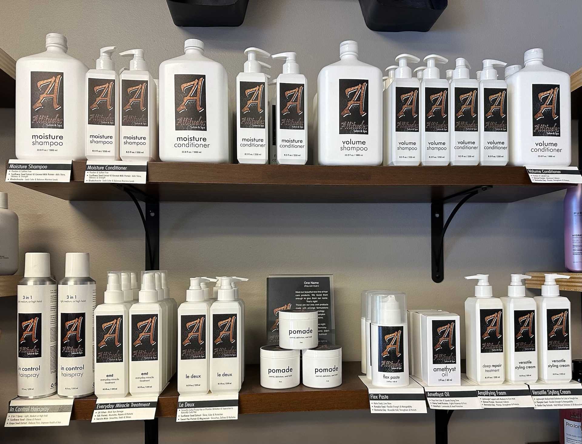 Shelves displaying various hair care products in white bottles with a stylized "A" logo.