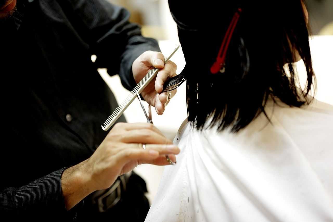 Hairdresser trimming a client's hair with scissors.